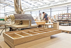 A carpentry workshop with wooden furniture pieces and a craftsman in the background.